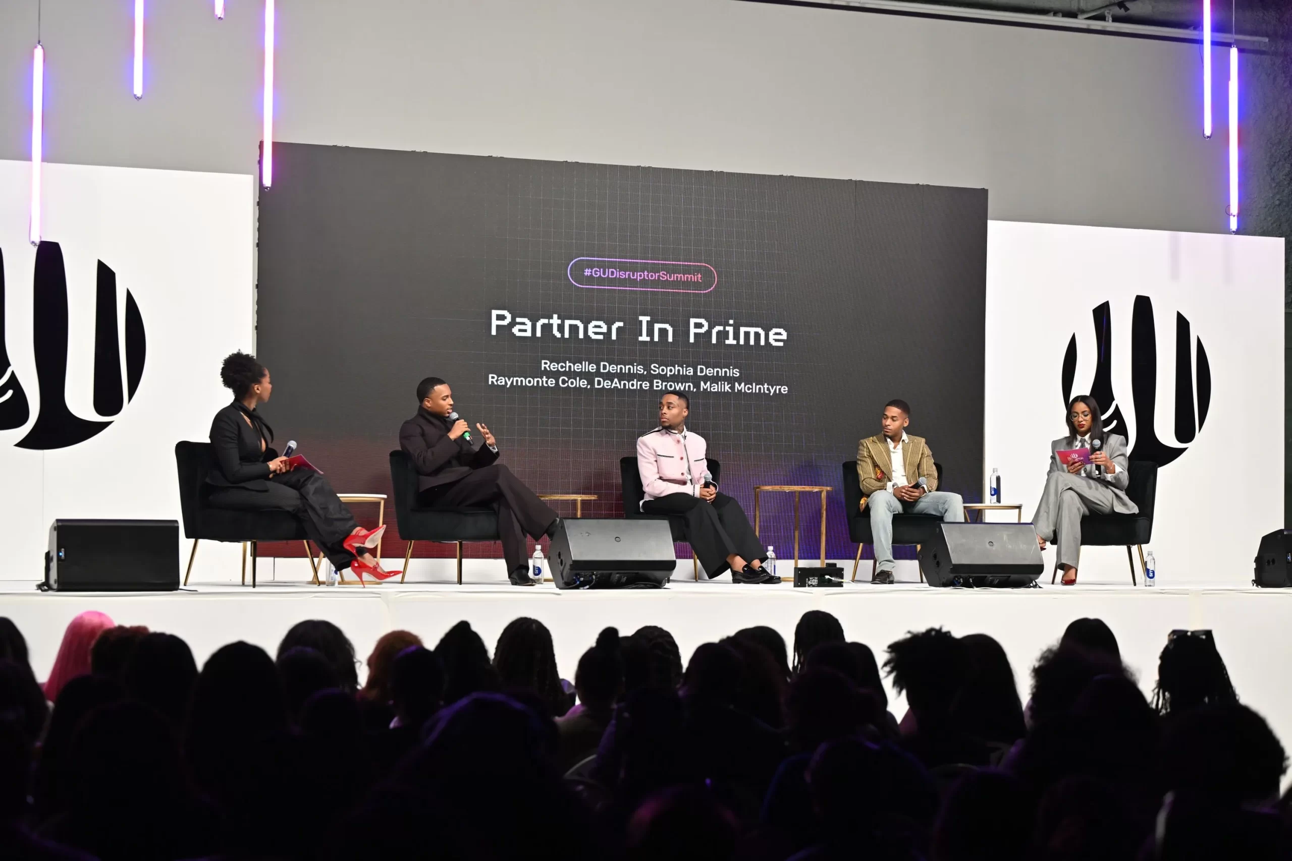 Five people sit on a stage panel labeled "Partner In Prime" at a summit event, speaking to an audience in a modern, well-lit venue.